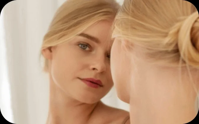 Woman looking in mirror - Simplified Skincare Routine